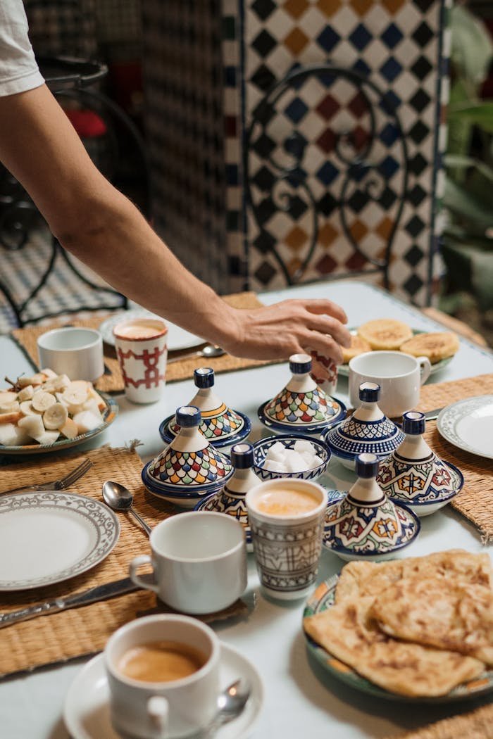 hero-img-01 A beautifully arranged Moroccan breakfast table with colorful ceramics and traditional dishes.
