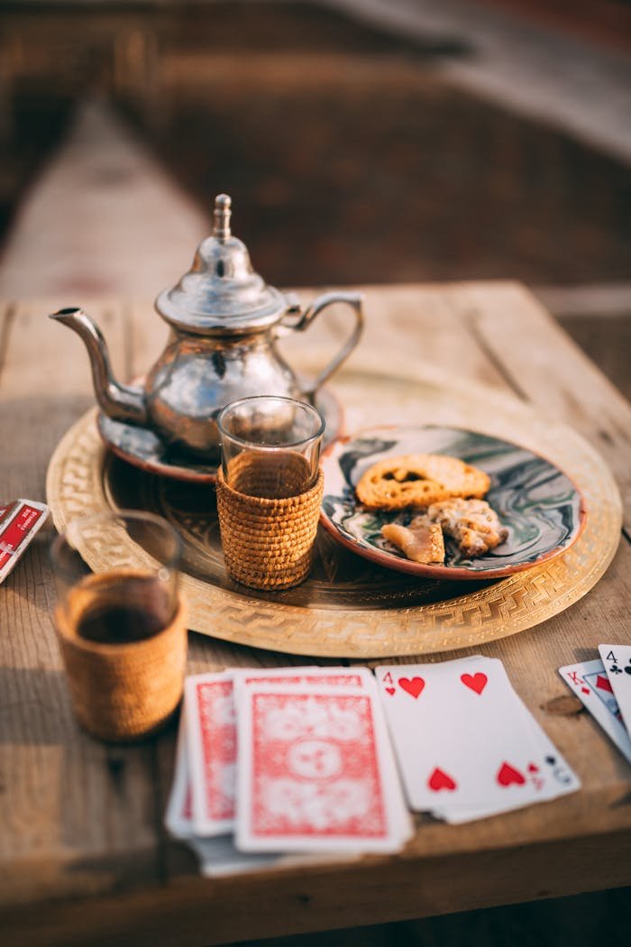 hero-img-02 Authentic Moroccan tea setup with playing cards on a rustic wooden table in Marrakesh.