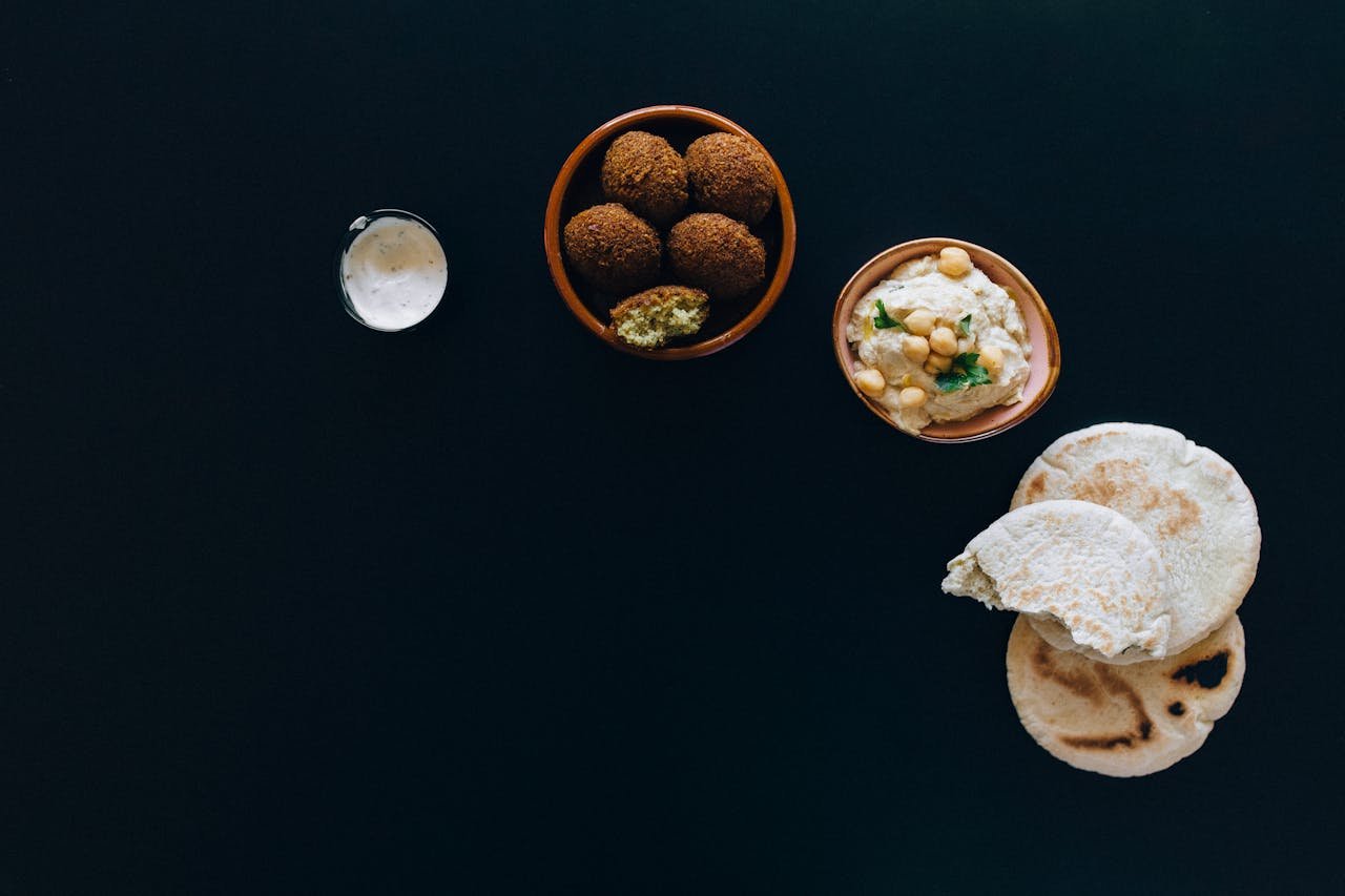 why-choose-us A delicious spread of falafel, hummus, and pita bread on dark background.